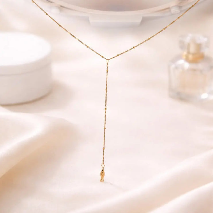 Gold necklace on a soft beige fabric background