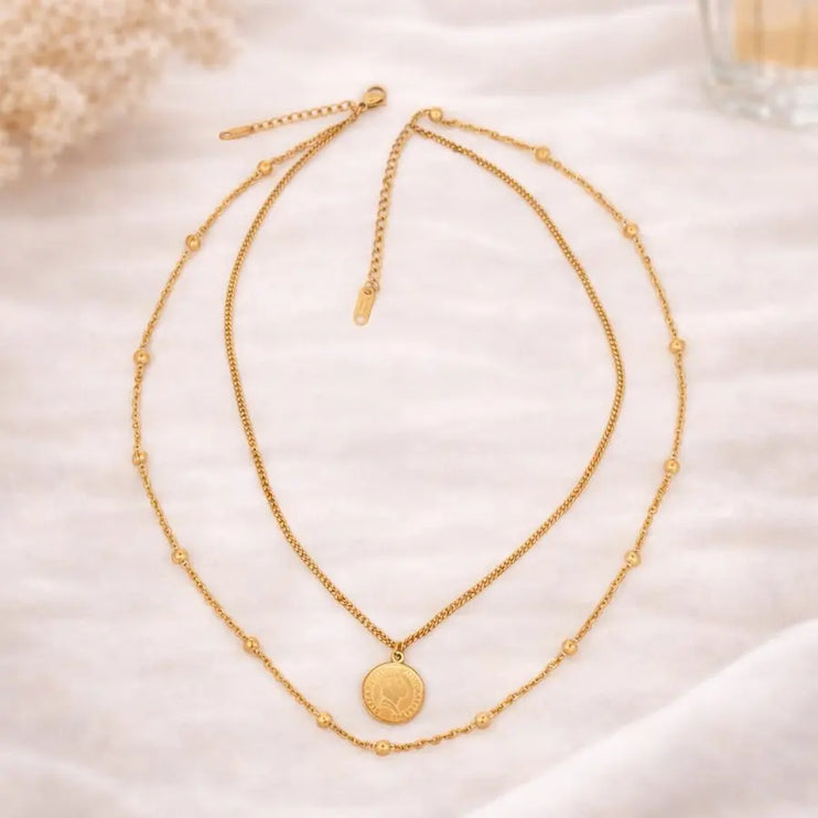 Two gold necklaces on a soft white fabric background