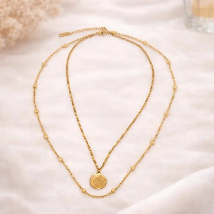 Two gold necklaces on a soft beige background