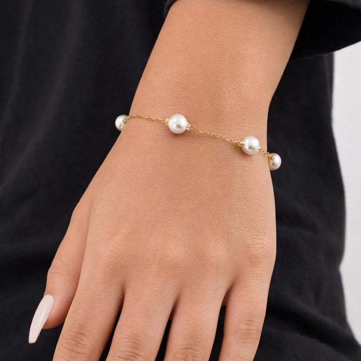 Pearl bracelet on a person's wrist against a black background