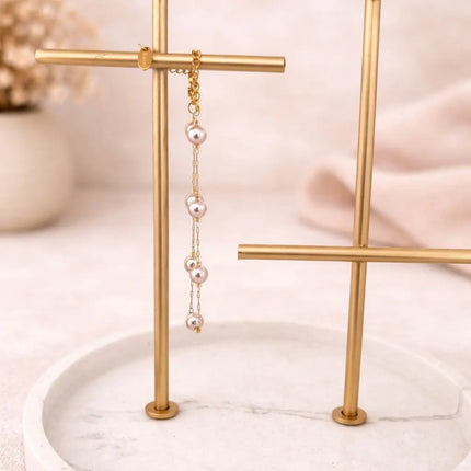 Pearl earring on a gold stand with a soft pink background