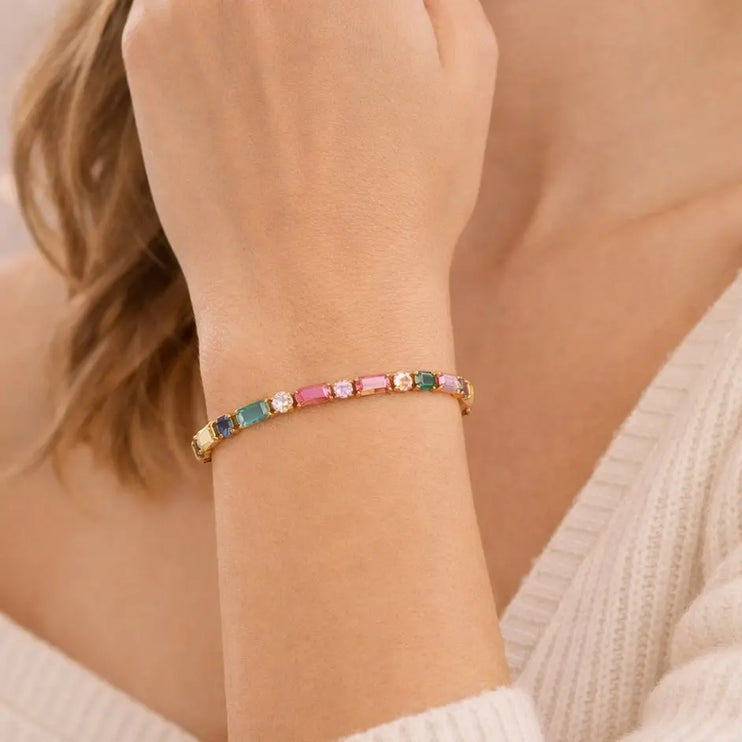 Close-up of a hand wearing a colorful beaded bracelet on a neutral background