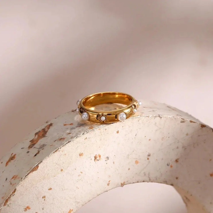 Gold ring with pearls on a textured beige surface