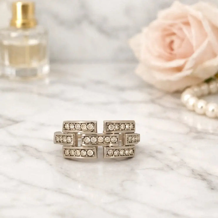 Set of three diamond rings on a marble surface with a perfume bottle and pink rose in the background.