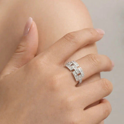 Silver ring with diamonds on a hand against a neutral background