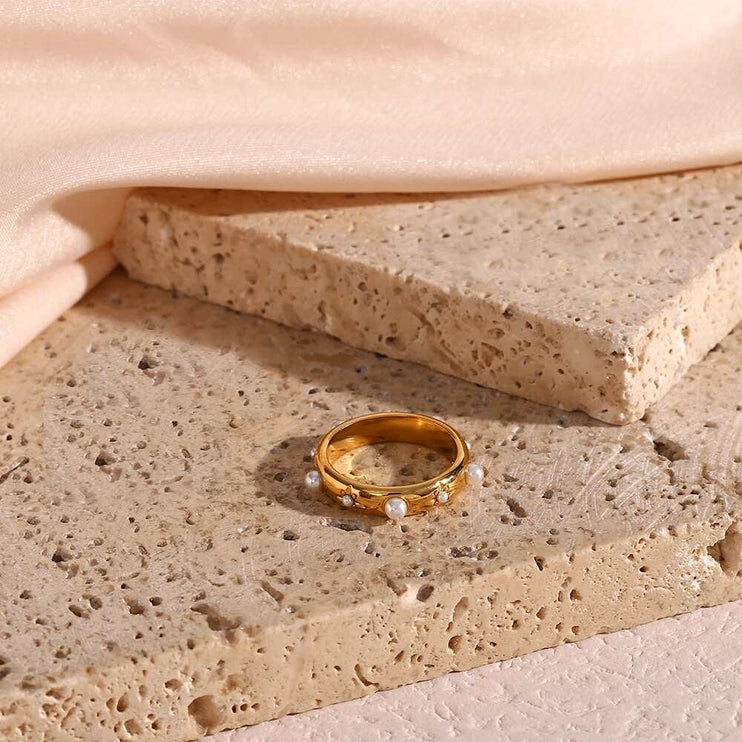 Gold ring with pearls on a textured stone surface