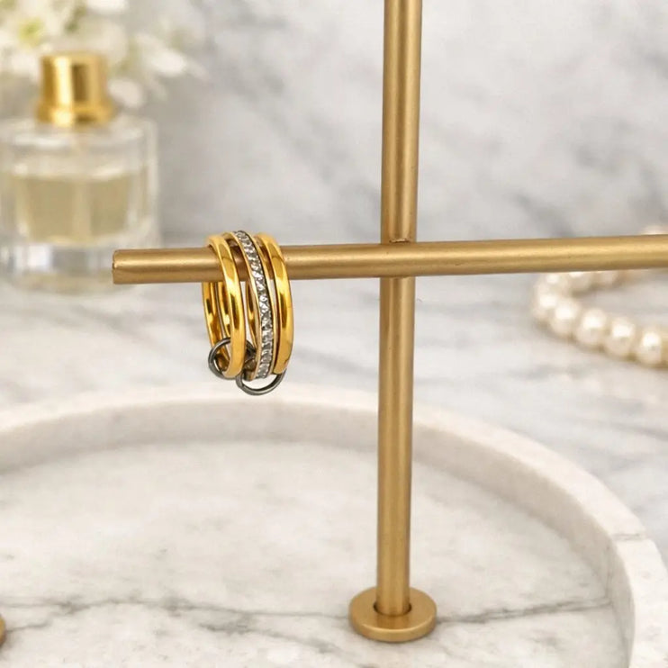 Gold hoop earrings on a gold stand with a marble background