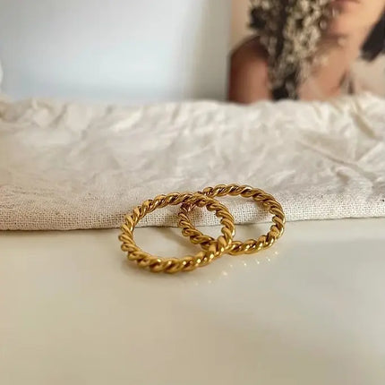 Gold hoop earrings on a textured fabric surface