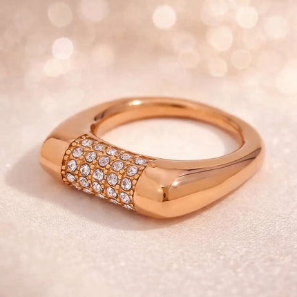 Rose gold ring with diamond accents on a soft pink background