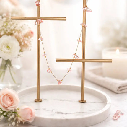 Necklace on a gold stand with flowers and candles in the background