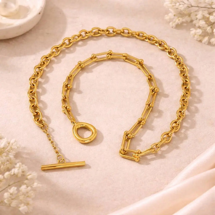 Gold chain necklace with clasp on a soft beige background