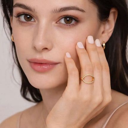 Woman wearing a gold ring on her finger with a neutral background
